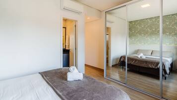 A modern hotel room with a large bed, a separate seating area, and a mirrored wall reflecting the bedroom.