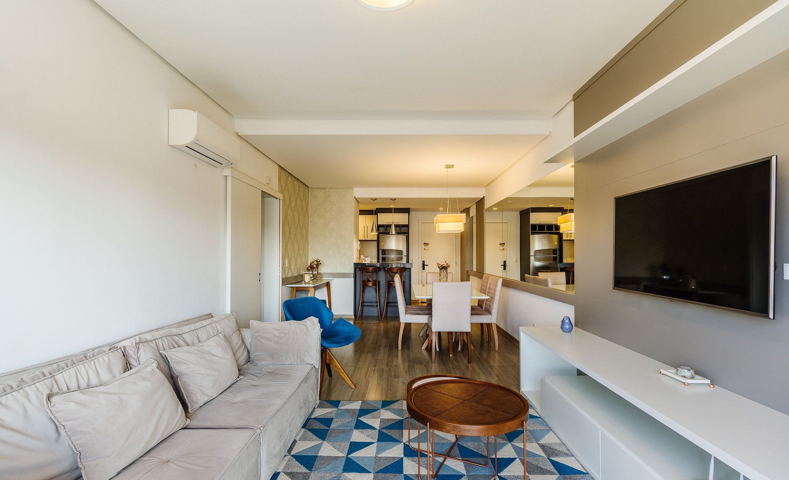A modern living room with a sofa, a dining area, and a kitchen in the background.