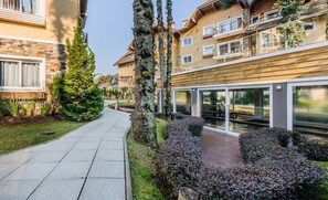 Un edificio residencial moderno con un camino pavimentado, setos bien recortados y una pequeña fuente de agua.