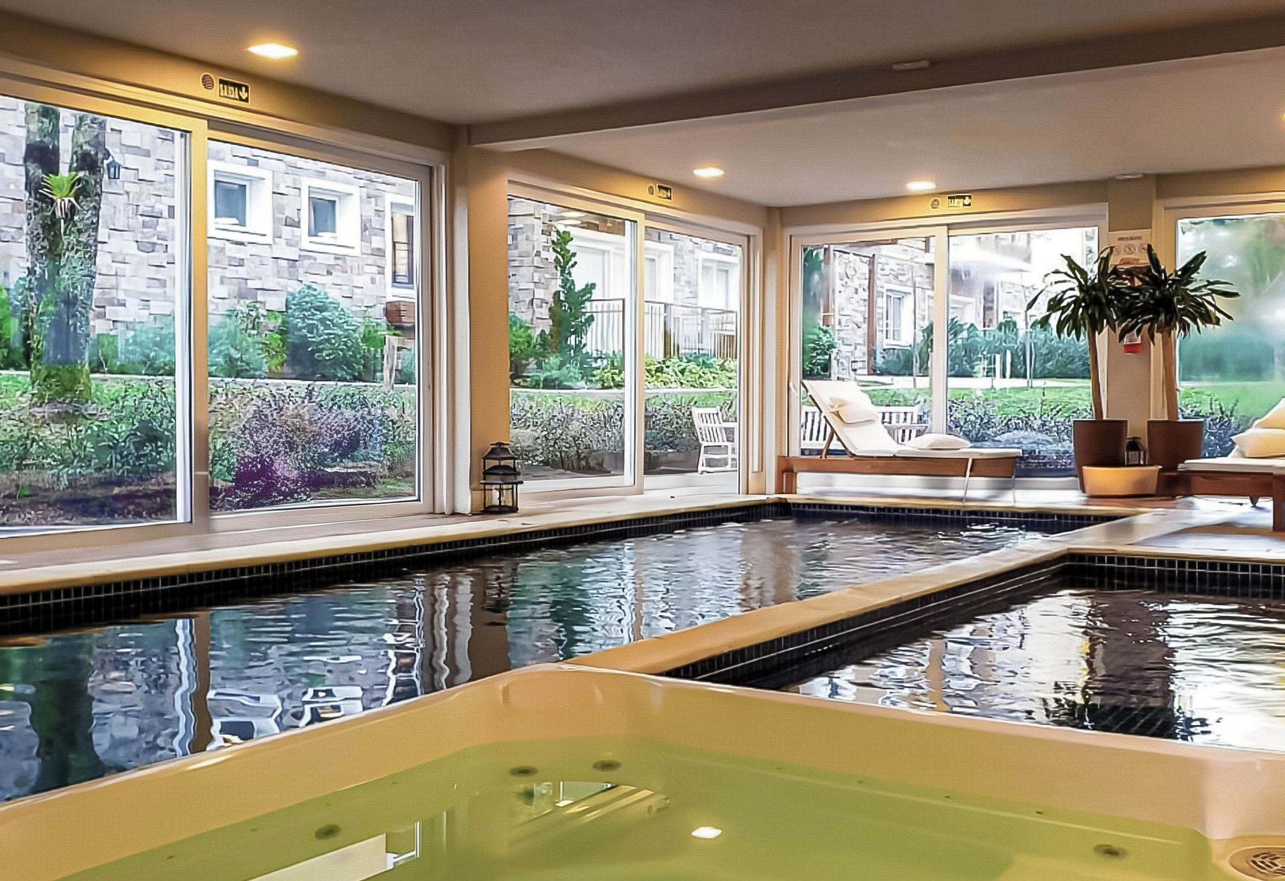 A pool area with a hot tub, large windows, and outdoor seating.