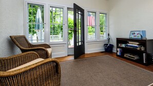 A room with wicker chairs, a bookshelf, and large windows with curtains. - Union Pier Cottage Close To Beach! (2 Nt Min!) (Union Pier)