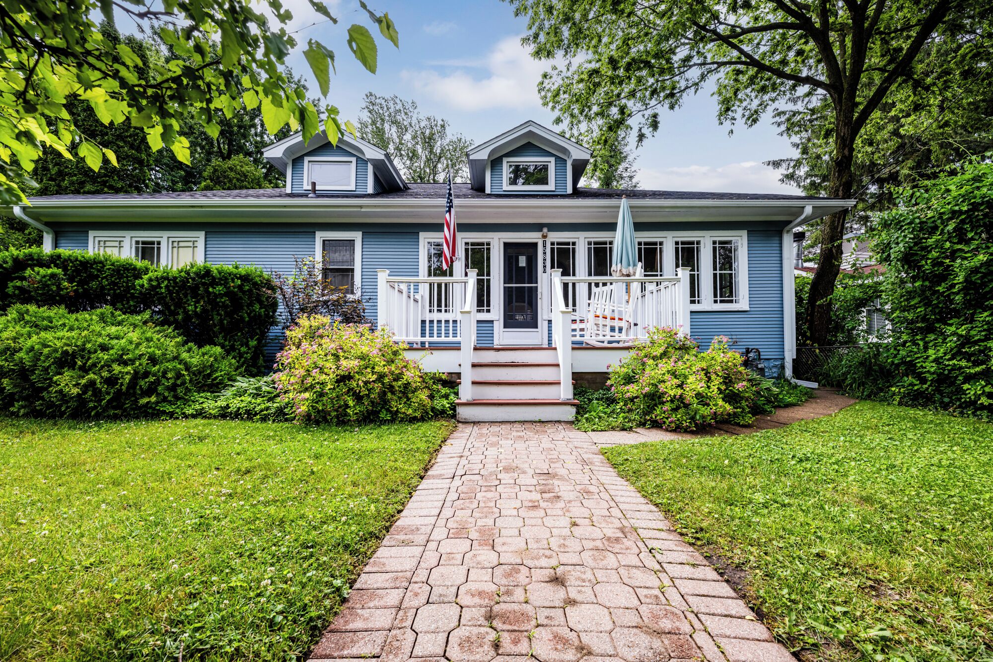 A two-story house with a front porch, a garage, and a well-maintained lawn.