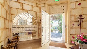 A lobby with a large arched window, a reception desk, a bench, and a wall-mounted display with letters. - Royal Hideaway – Estoril 2BR Pool Retreat (Cascais)
