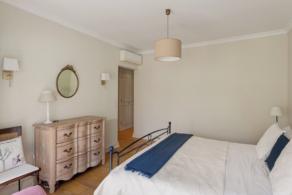 Un dormitorio con cama, cómoda, espejo y lámparas de noche.