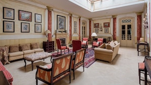 A spacious living room with a high ceiling, a fireplace, and a large window. - Royal Hideaway – Estoril 2BR Pool Retreat (Cascais)
