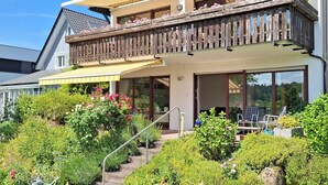 A two-story building with a balcony, outdoor seating, and a garden. - Large vacation apartment with terrace at the entrance to the northern Black Forest. Quiet residential area (Gaggenau)