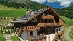 Een houten chalet met twee verdiepingen en een balkon, gelegen in een bergachtig gebied.