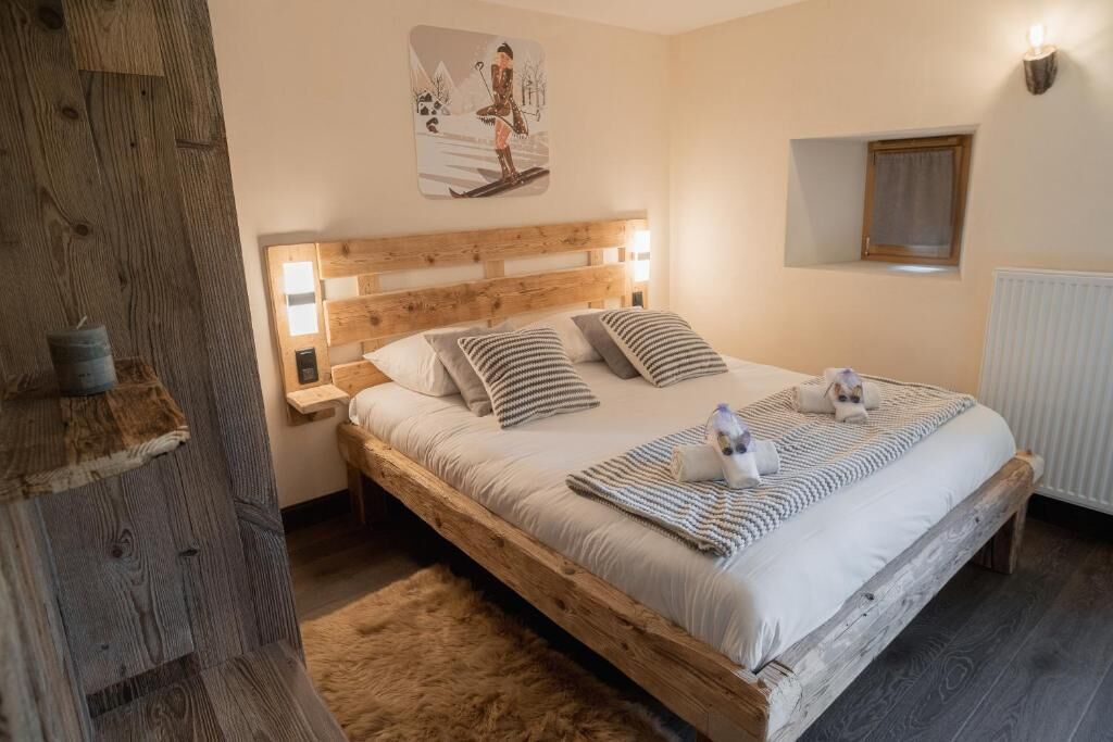 A wooden bed with a headboard, two bedside tables, a wall-mounted light, a window, and a radiator.