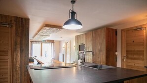 Een moderne keuken met een groot eiland, houten wanden en een hanglamp.