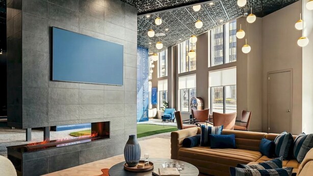 A modern lounge area with a flat-screen TV, a fireplace, leather sofas, and a dining table.