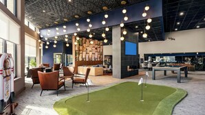 A modern indoor space with a pool table, seating area, and a green turf area. - Designer 2BR | Gym, Parking (White Plains)
