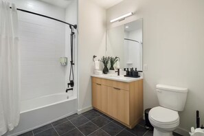 A modern bathroom with a shower, toilet, and vanity. - Designer 2BR | Gym, Parking (White Plains)