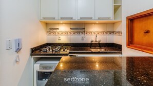 Eine Küche mit weißen Schränken, einer schwarzen Granitarbeitsplatte, einer Edelstahlspüle und einem eingebauten Backofen.