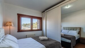 Ein Schlafzimmer mit zwei Betten, einem Fenster mit Blick, einer Lampe und einer Heizung.