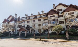 Um edifício residencial de vários andares com fachada simétrica, várias chaminés e um portão de entrada.