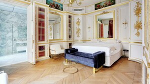 A luxurious bedroom with a large bed, a vanity with a mirror, and a chandelier.