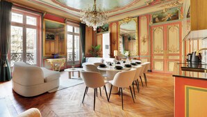 A dining area with a round table set for six, surrounded by white chairs.
