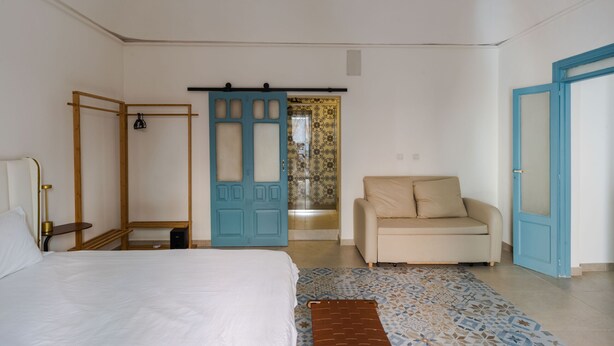 Un dormitorio con cama, sofá, armario y puerta que da al baño.