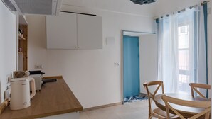 Una cocina con cafetera, un lavamanos y una puerta azul.