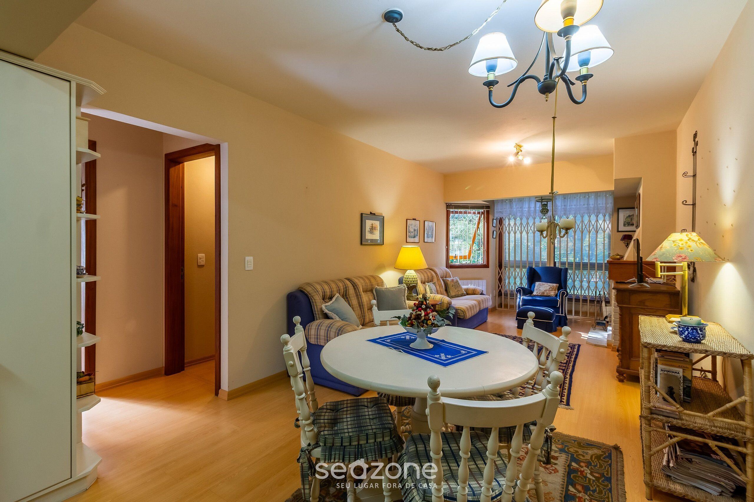 A cozy living room with a round dining table, a sofa, and a blue armchair.