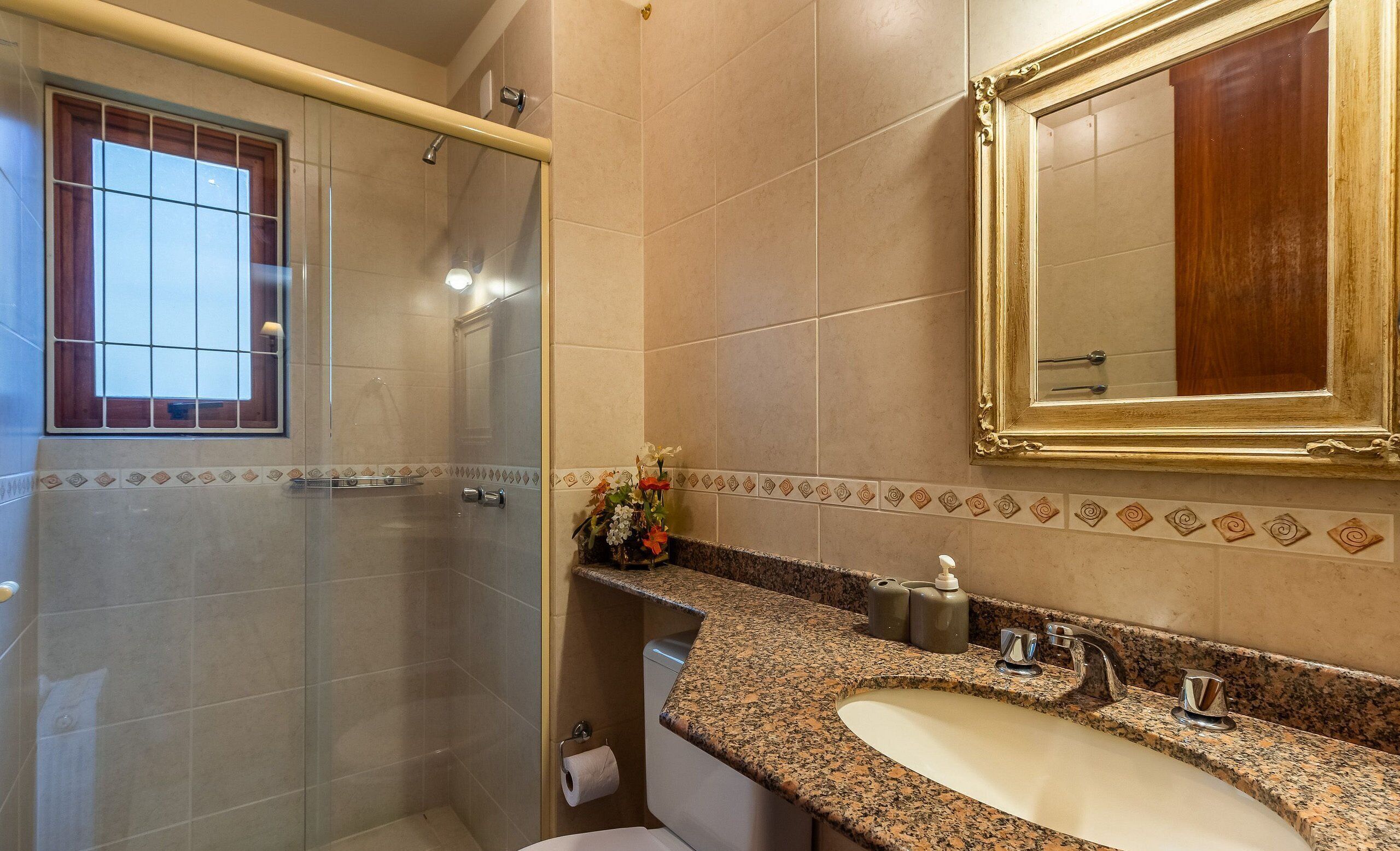 A bathroom with a shower, toilet, sink, and a large mirror.