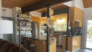 A modern kitchen with wooden cabinets, a central island, and a dining area with a brown sofa.