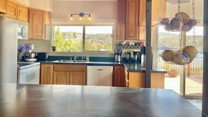 A kitchen with wooden cabinets, a stainless steel sink, and a window with a view of the outdoors.