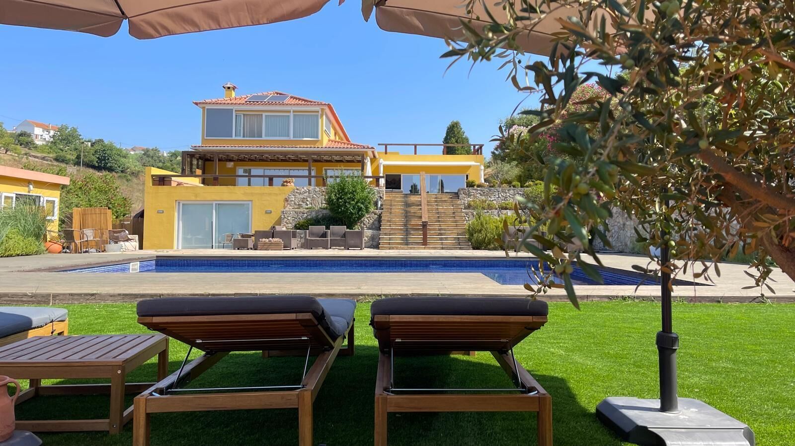 A modern two-story house with a swimming pool, outdoor seating, and a well-maintained garden.