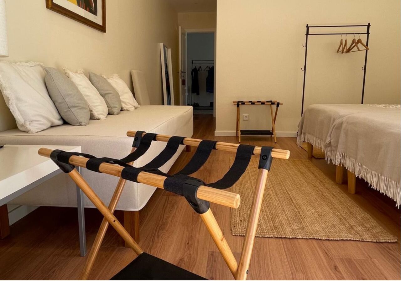Ein Zimmer mit Holzstuhl, einem Bett, einem kleinen Tisch und einem Kleiderständer.