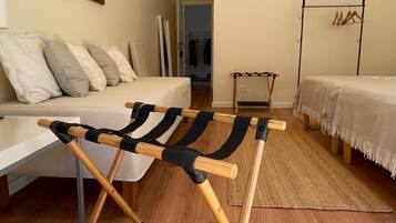 Ein Zimmer mit Holzstuhl, einem Bett, einem kleinen Tisch und einem Kleiderständer.