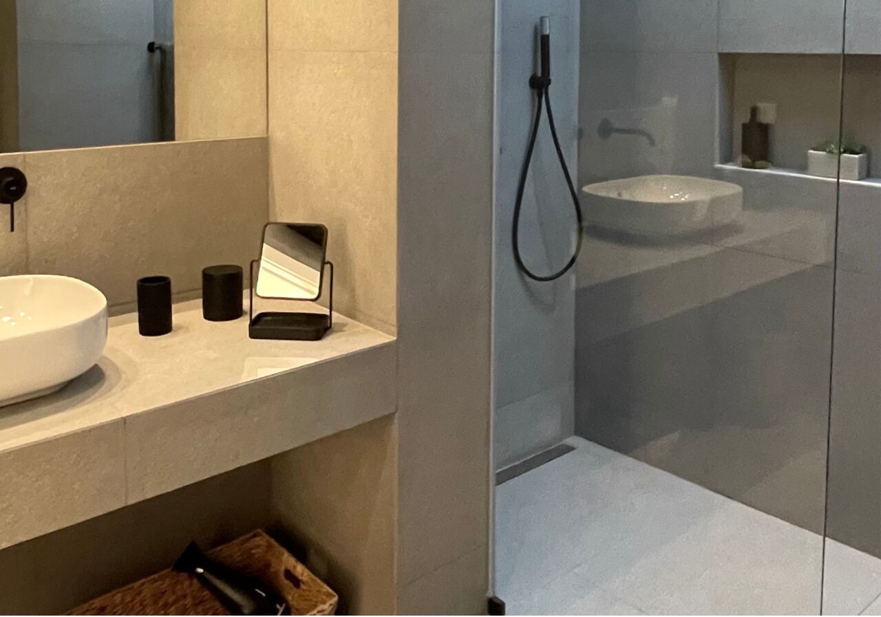 A modern bathroom with a large sink, a mirror, and a handheld showerhead.