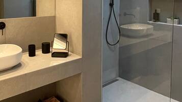 A modern bathroom with a large sink, a mirror, and a handheld showerhead.