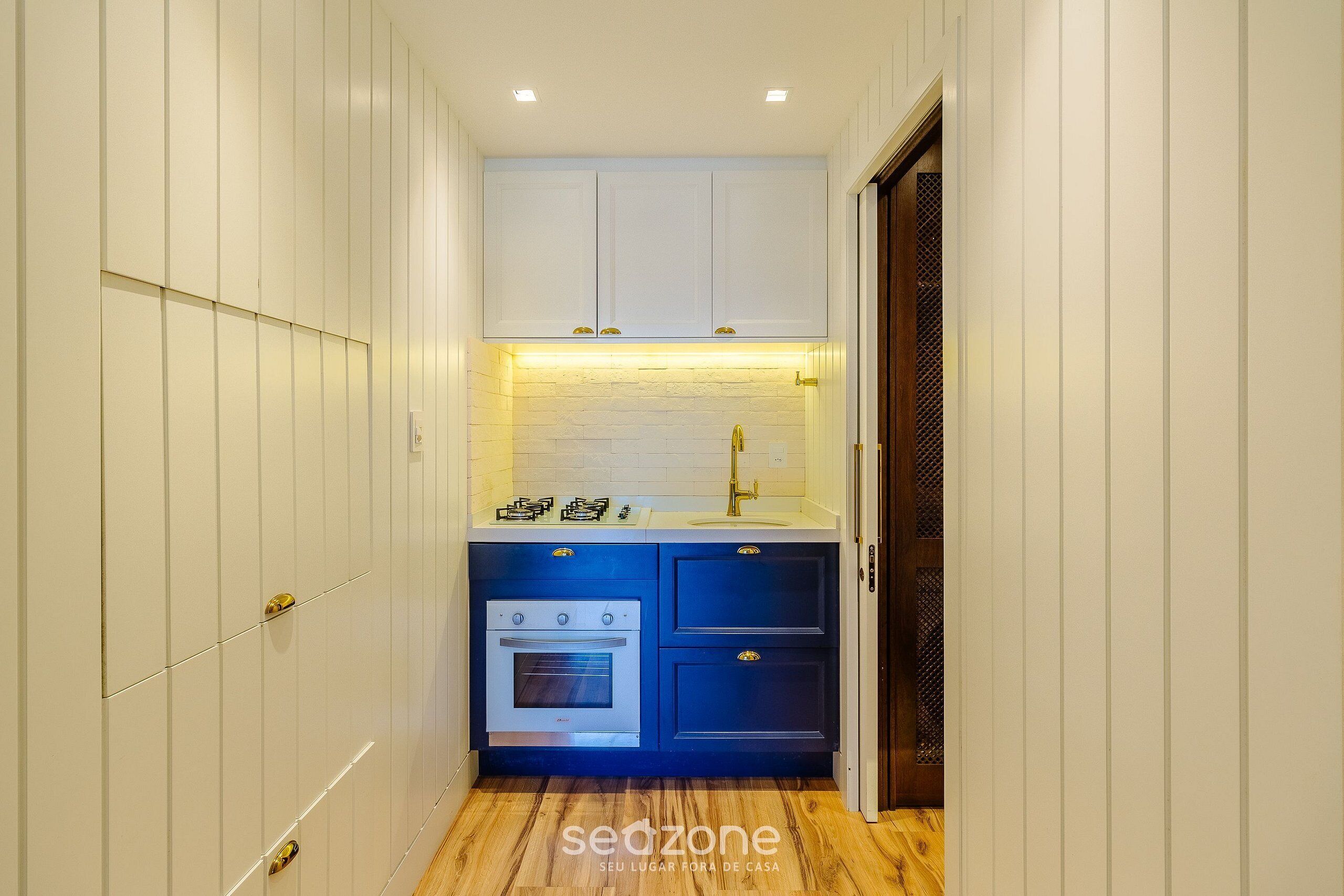 A narrow kitchen with white cabinets, a blue countertop, and a built-in oven.
