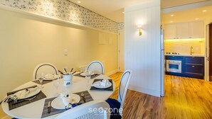 A dining area with a table set for four, chairs, and a kitchen visible in the background. - Beautiful Apt. in the Center of Gramado-rs Lar0406 (Gramado)
