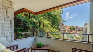A balcony with stone walls, a wooden table, and chairs. - Beautiful Apt. in the Center of Gramado-rs Lar0406 (Gramado)