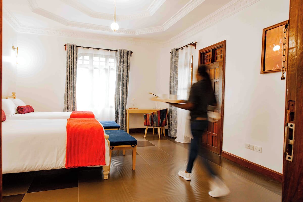 A hotel room with two beds, a desk, and a chair.