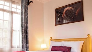 A neatly made bed with a wooden headboard, a red throw blanket, and a white comforter. - The Hidden Valley Lodge (Arusha)