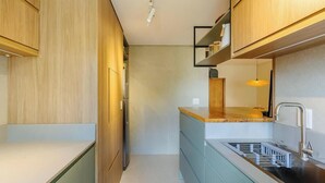 Una cocina moderna con armarios de madera, un lavamanos de acero inoxidable y un lavavajillas empotrado.