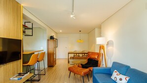 Una sala de estar moderna con televisor, zona de estar y comedor.