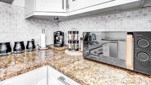 A kitchen with white cabinets, a granite countertop, a coffee maker, a toaster, and a microwave. - Wimbledon/Discount/Ensuite/Close to AELTC&Station (London)