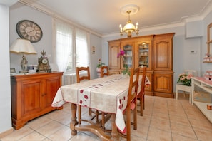 A dining room with a table set for four, wooden cabinetry, a clock on the wall, and a chandelier.