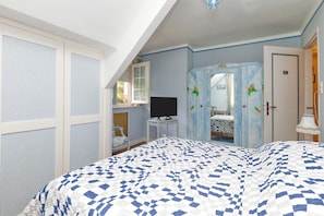 A bedroom with a bed, a television, a wardrobe, and a window.