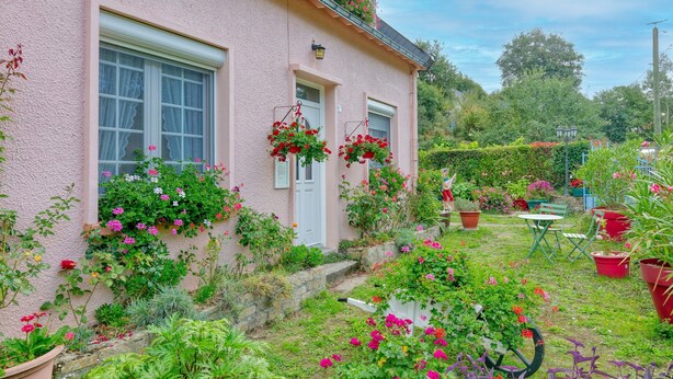 Una casa rosa con jardín, una puerta y una ventana.