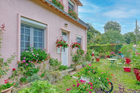 A pink house with a garden, a door, and a window.