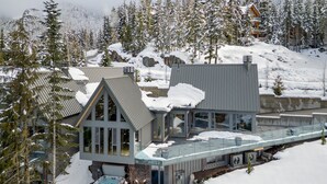 Une station de ski moderne dotée d’un grand jacuzzi en verre, d’un chalet en bois et offrant une vue imprenable sur les montagnes.