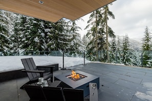 A fire pit table with chairs and a view of snow-covered trees. - Aurora Estate at Kadenwood (Whistler)