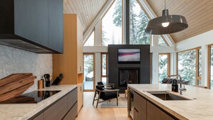 Une cuisine moderne dotée d’un grand îlot central, d’appareils électroménagers intégrés et d’une cheminée.