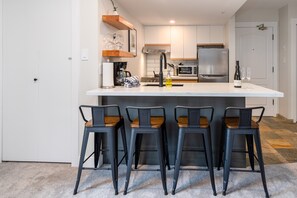 A modern kitchen with a central island, bar stools, and a refrigerator. - Big Mauna at the Marquise (Whistler)