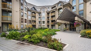Un hôtel à plusieurs étages doté de balcons, d’une entrée couverte et d’un jardin aménagé.