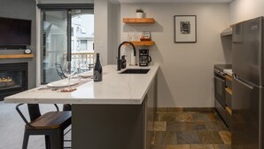 Une cuisine moderne dotée d’un plan de travail en marbre, d’une cuisinière encastrée, d’un réfrigérateur en acier inoxydable et d’une machine à café.